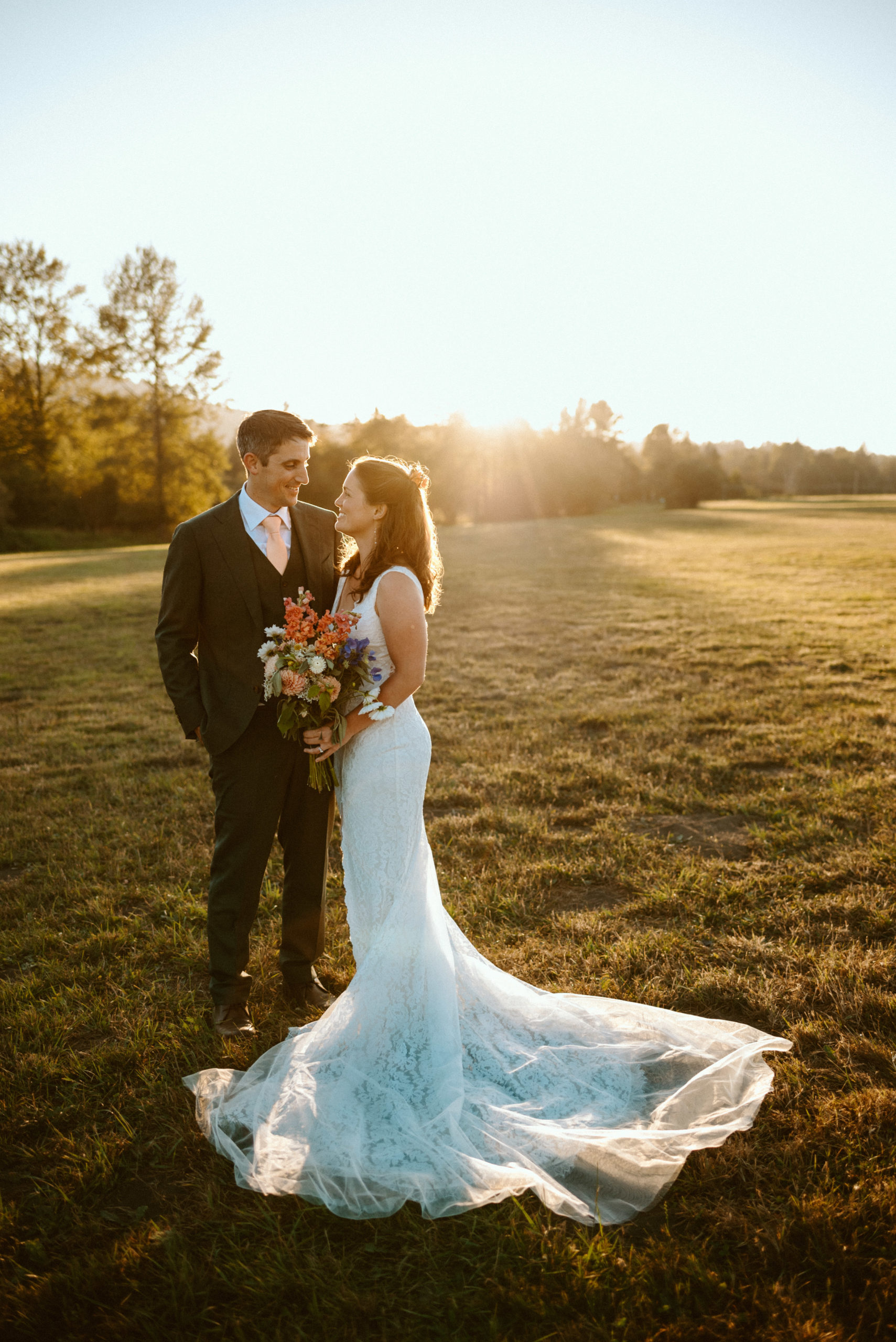 bride and groom in open field at sunset